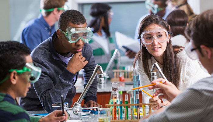 students gathered around beakers in lab